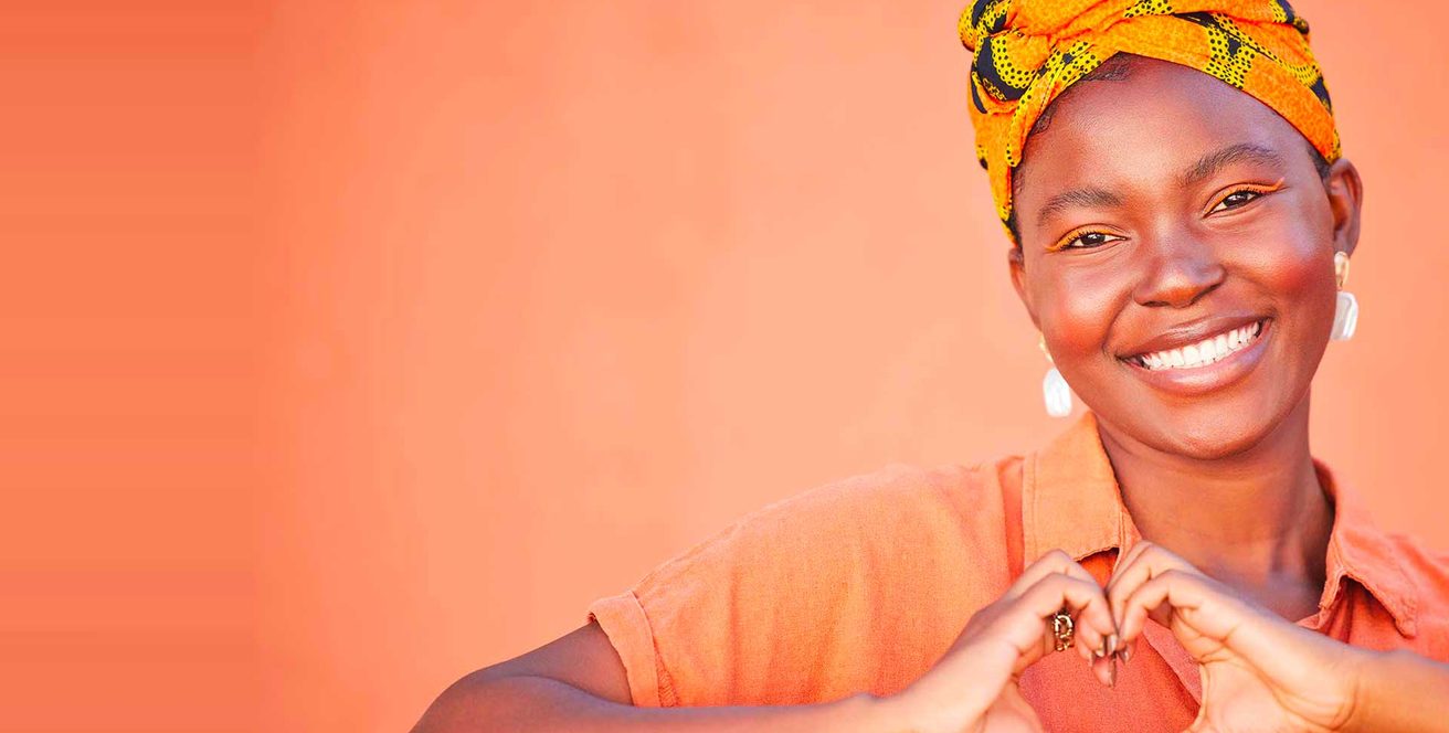 A smiling woman making a heart shape with her hands