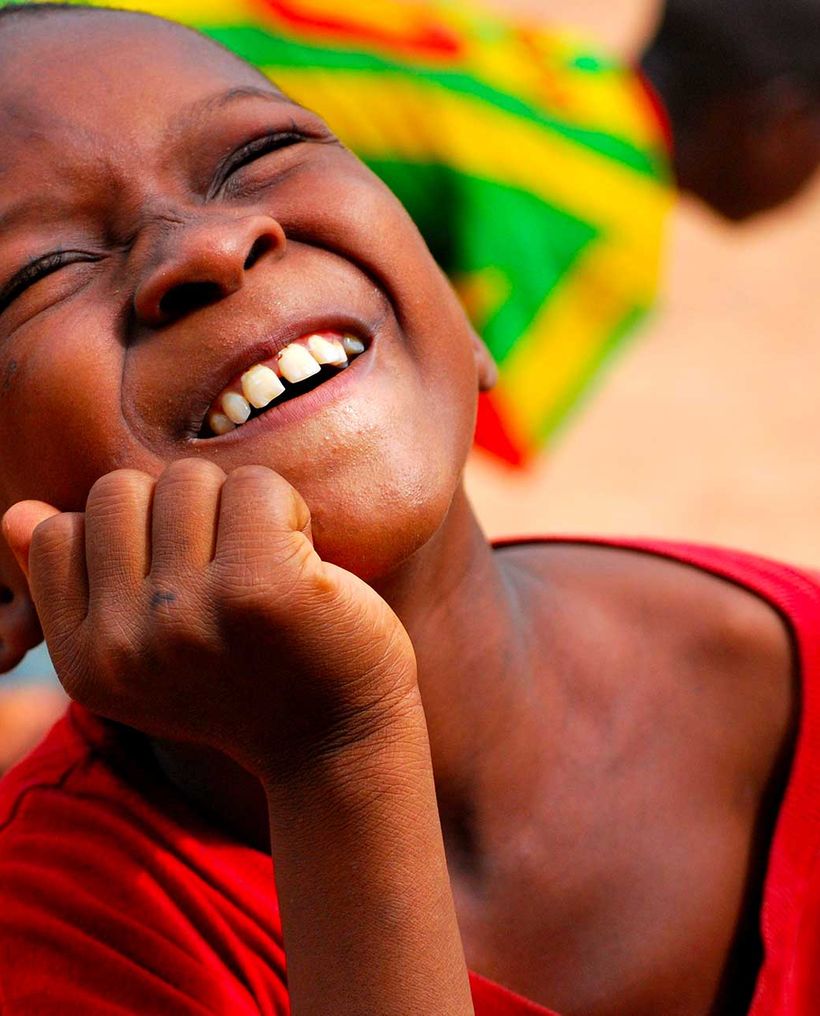 A boy laughing with his hand under his chin