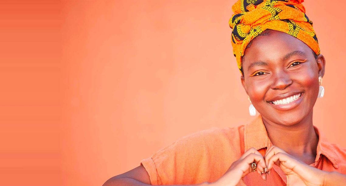 A smiling woman making a heart shape with her hands